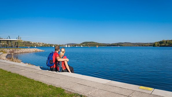 Der Bostalsee Ein junges Paar sitzt am Ufer des Bostalsees